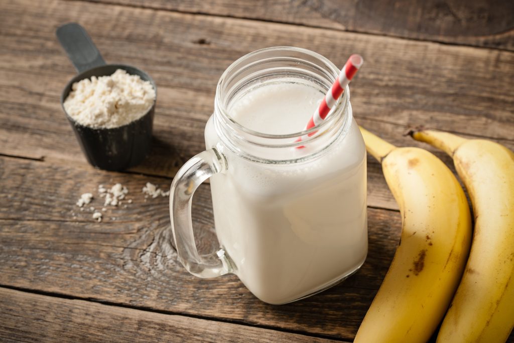 Whey protein cocktail and banana fruit on wooden table